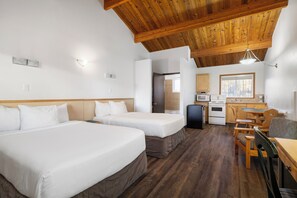 Habitación de hotel con dos camas, kitchenette y zona de comedor.