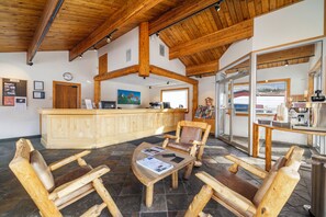 A wooden interior with a reception desk, seating area, and a view through a glass door.