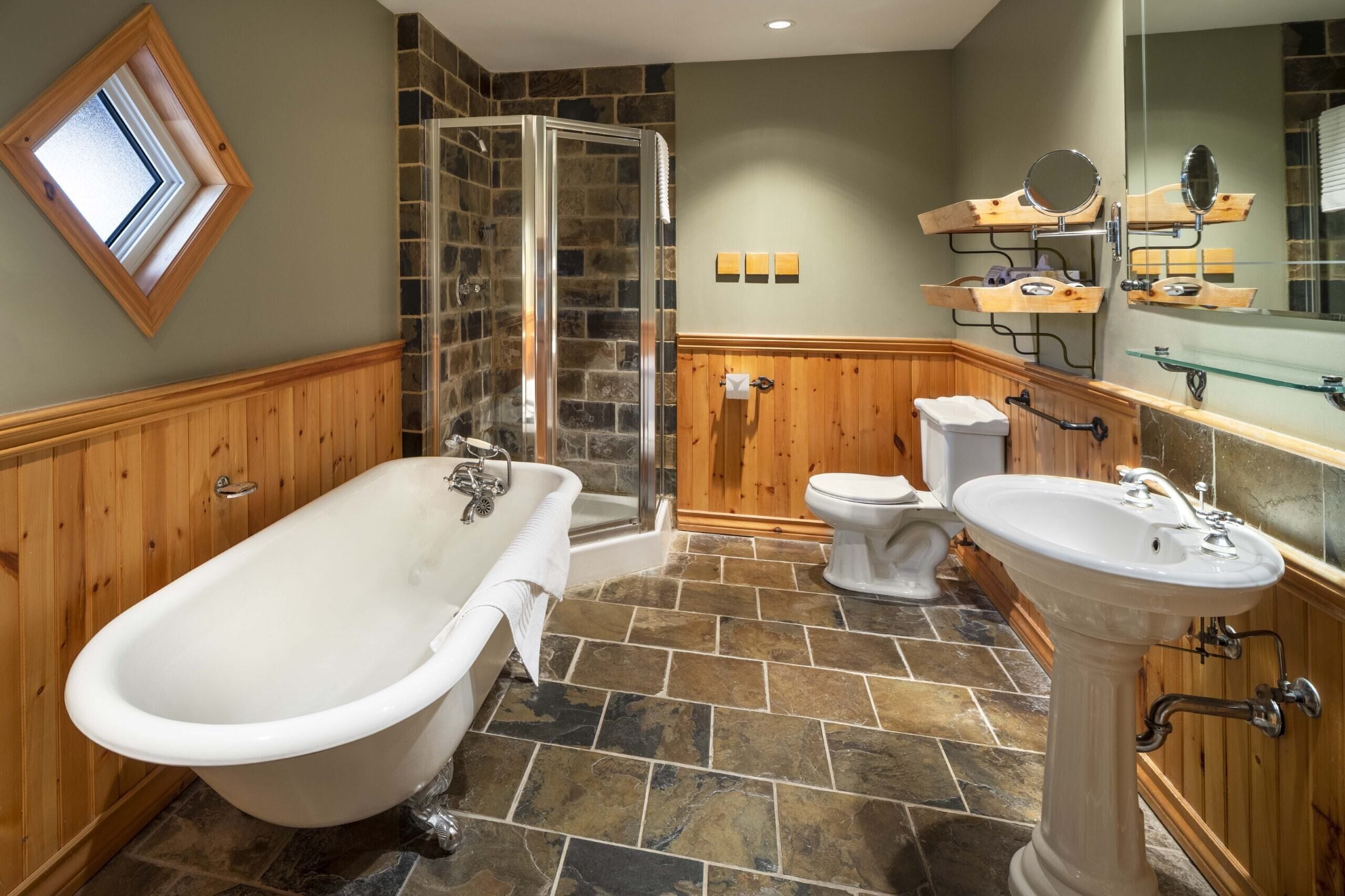 A bathroom with a freestanding bathtub, a glass-enclosed shower, a toilet, and a pedestal sink.