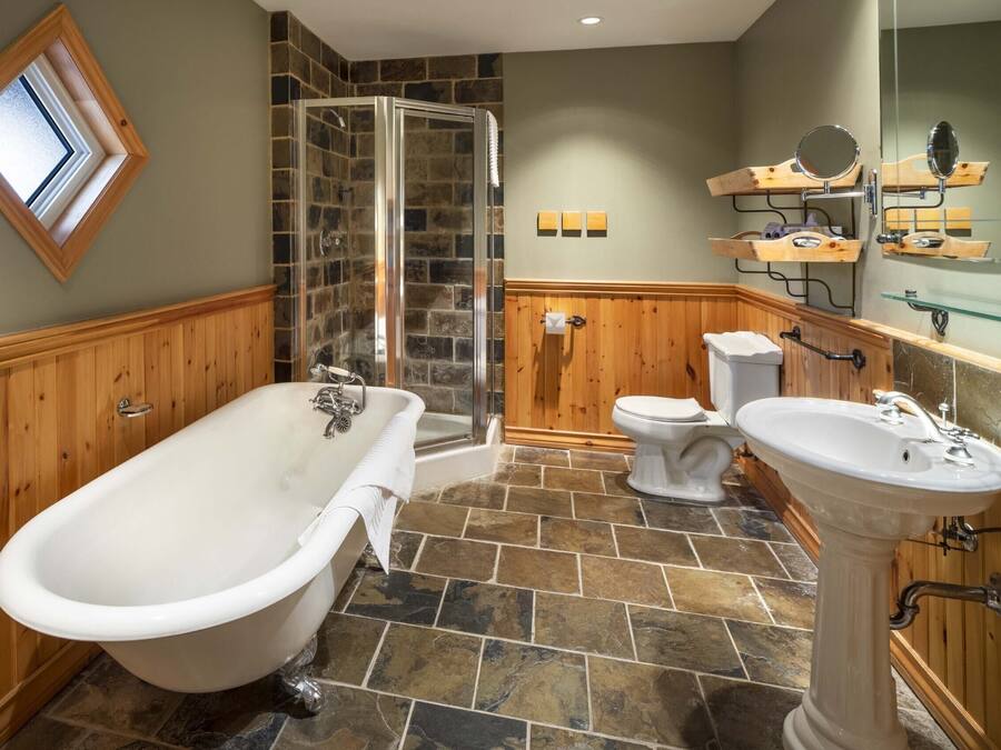 A bathroom with a freestanding bathtub, a glass-enclosed shower, a toilet, and a pedestal sink.