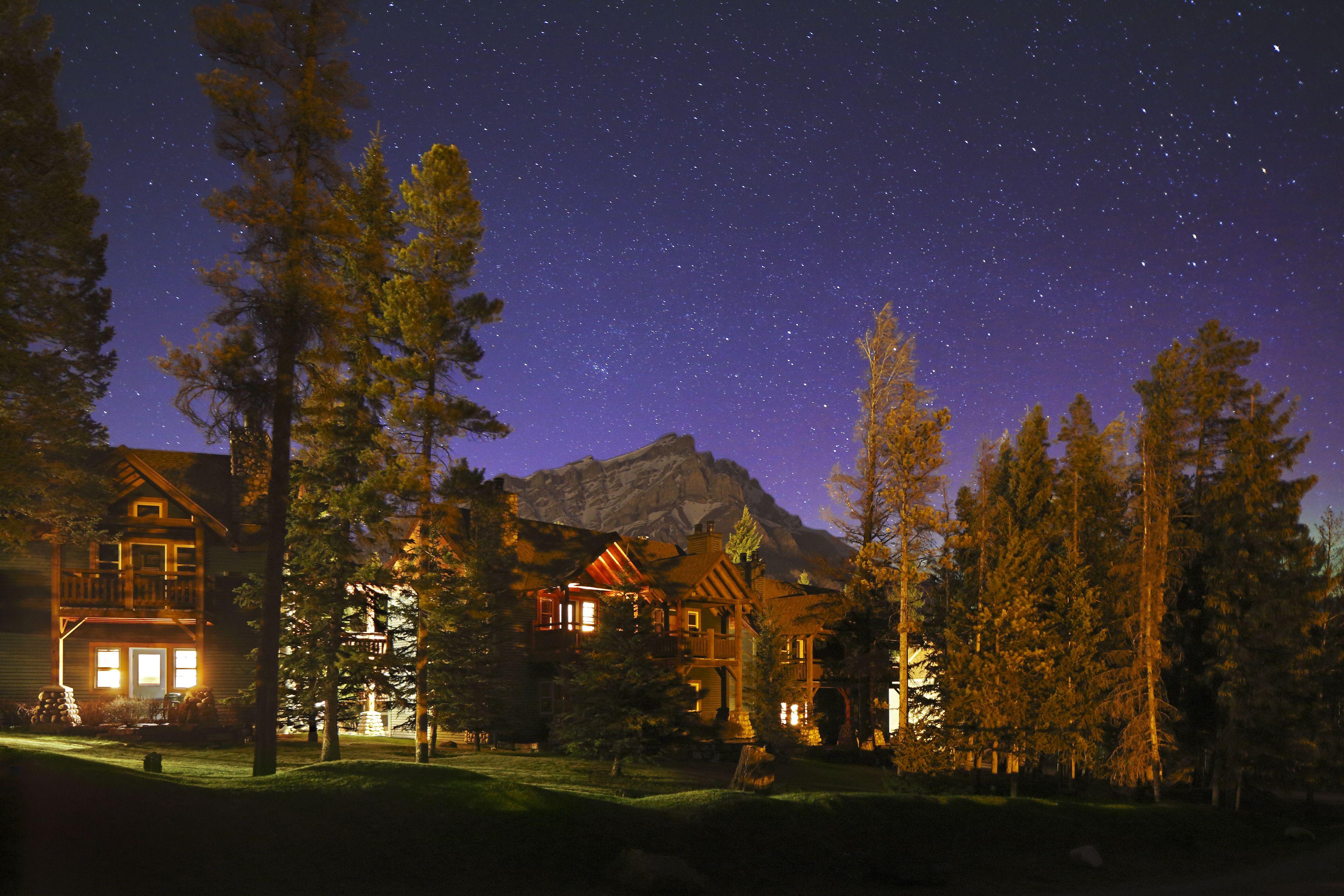 Un lodge con un ampio portico, diverse finestre e uno sfondo montuoso.