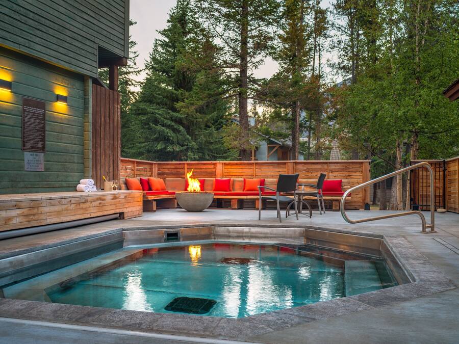 A hot tub area with a fire feature, wooden deck, and seating.