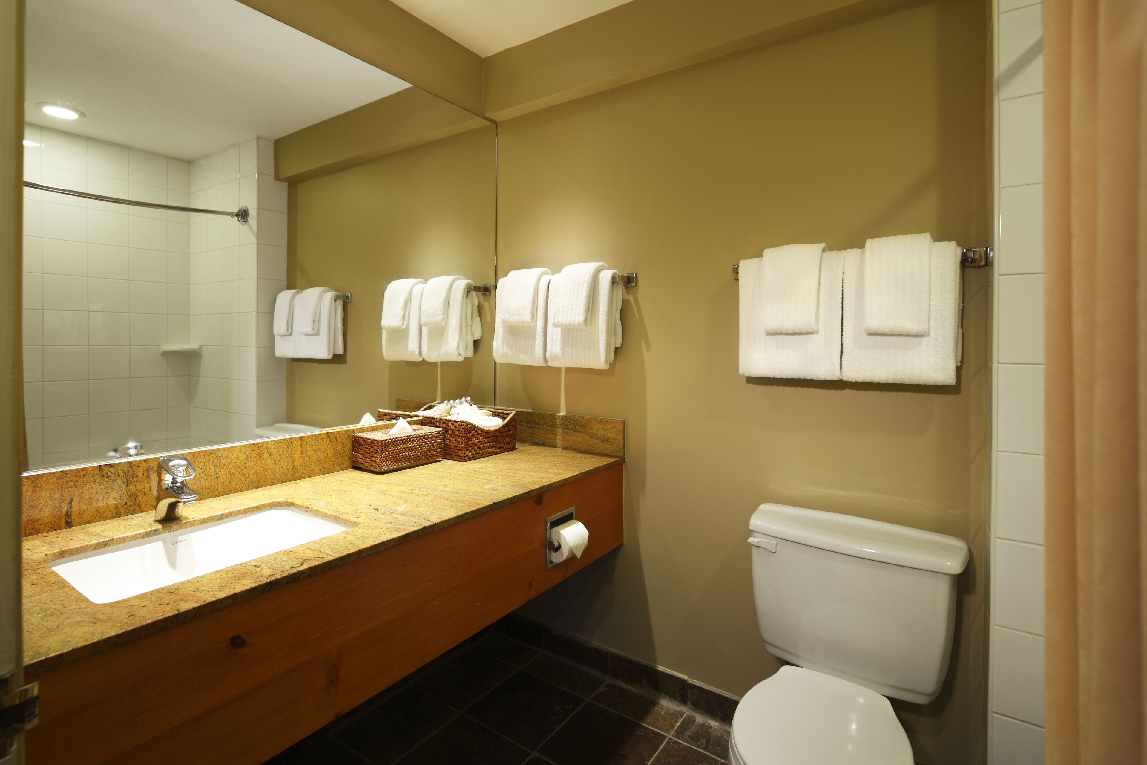 Un baño con lavamanos, espejo, toallero y retrete.