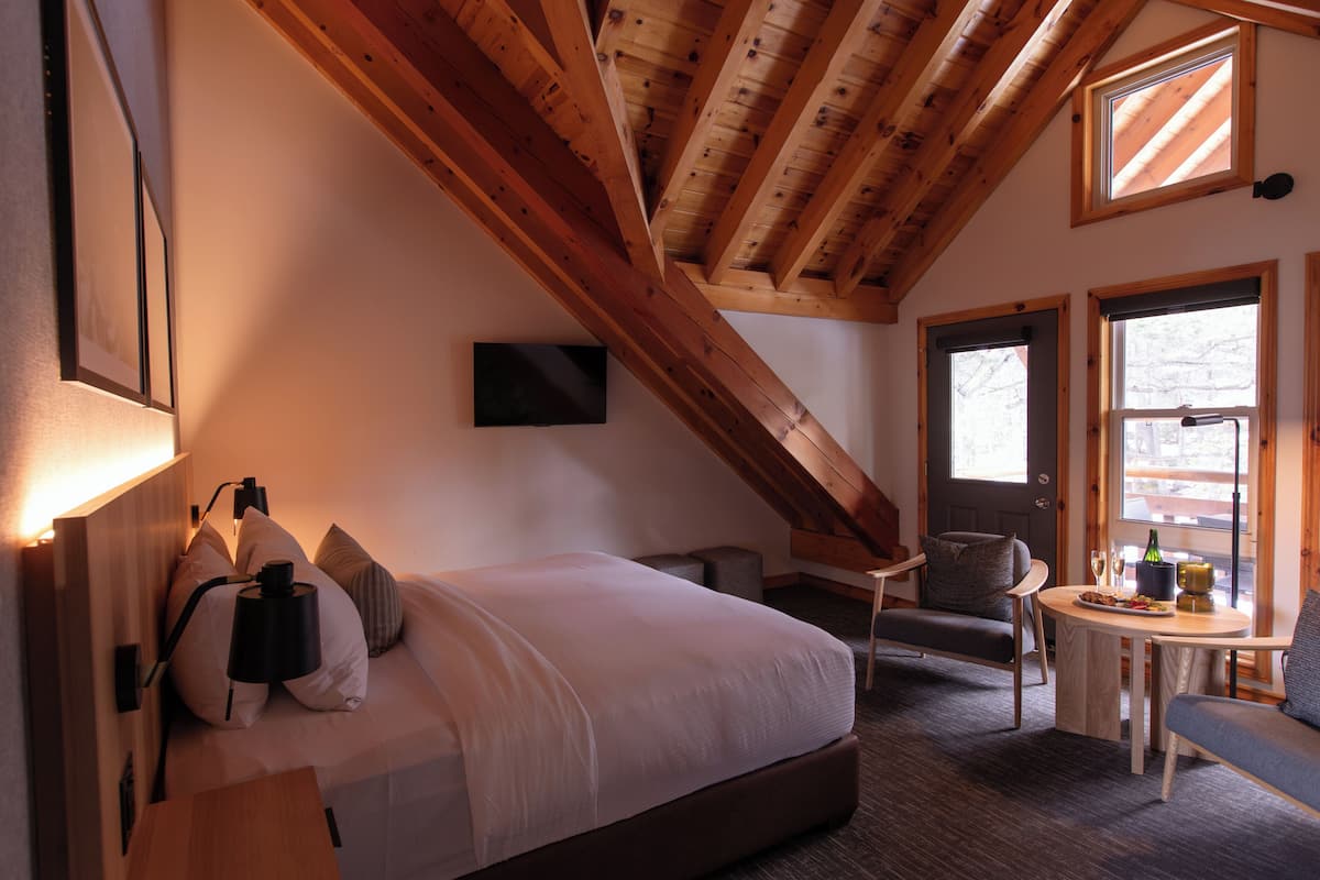 A bedroom with a bed, bedside table, lamp, and a window.