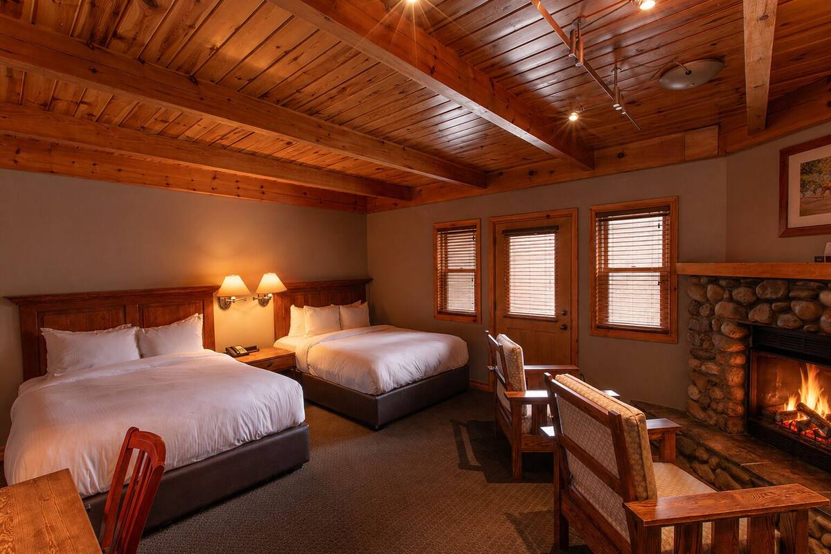 A room with two beds, a fireplace, and wooden ceiling beams.
