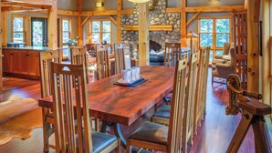 A spacious dining area with a large wooden table, multiple chairs, and a stone fireplace. - Buffalo Mountain Lodge (Banff)