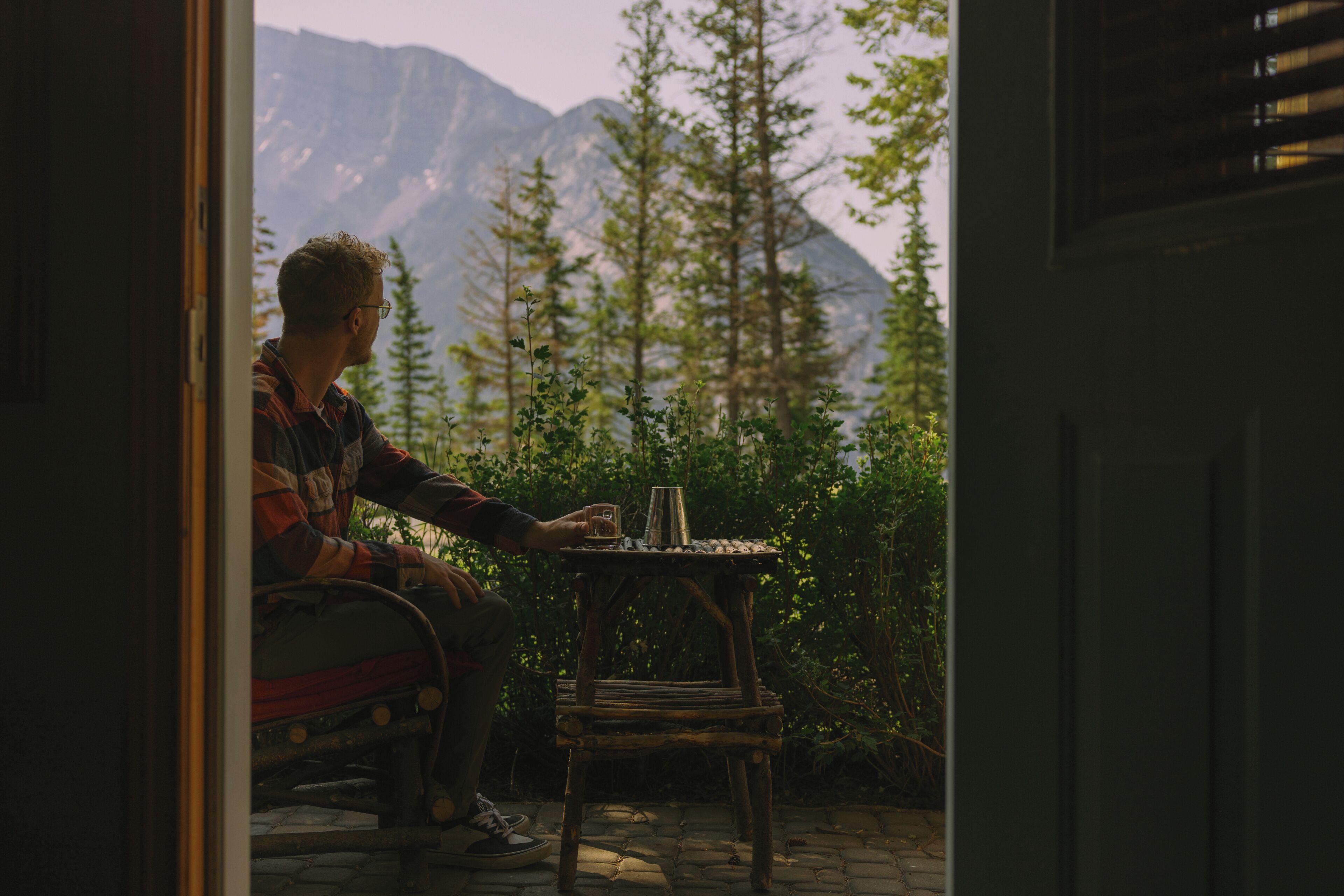 A person sitting at a table with a view of mountains and trees.