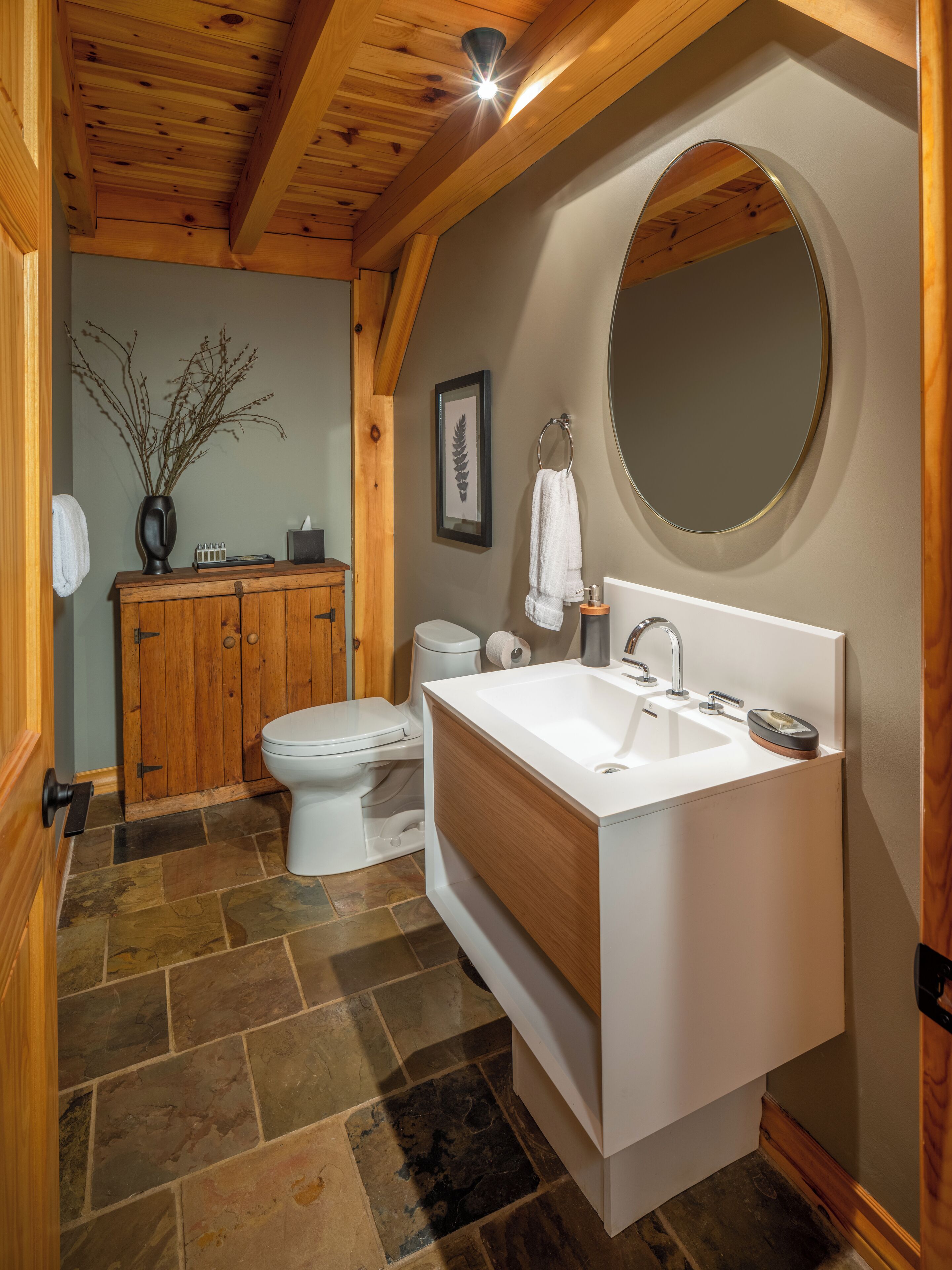Un baño con tocador de madera, inodoro y lavamanos.