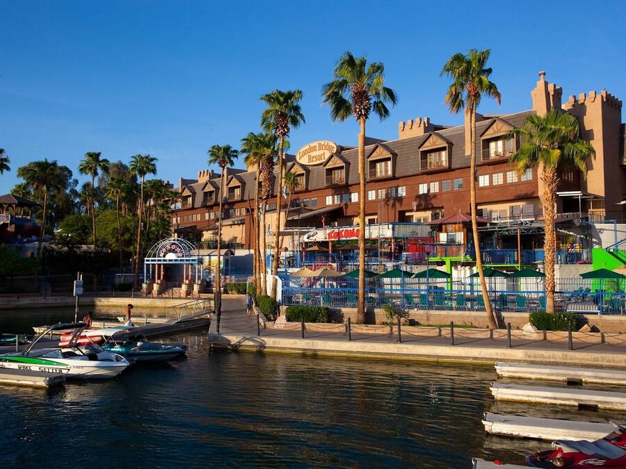 Een hotel aan het water met een zwembad, palmbomen en een bord met de tekst 'London Bridge Resort'.