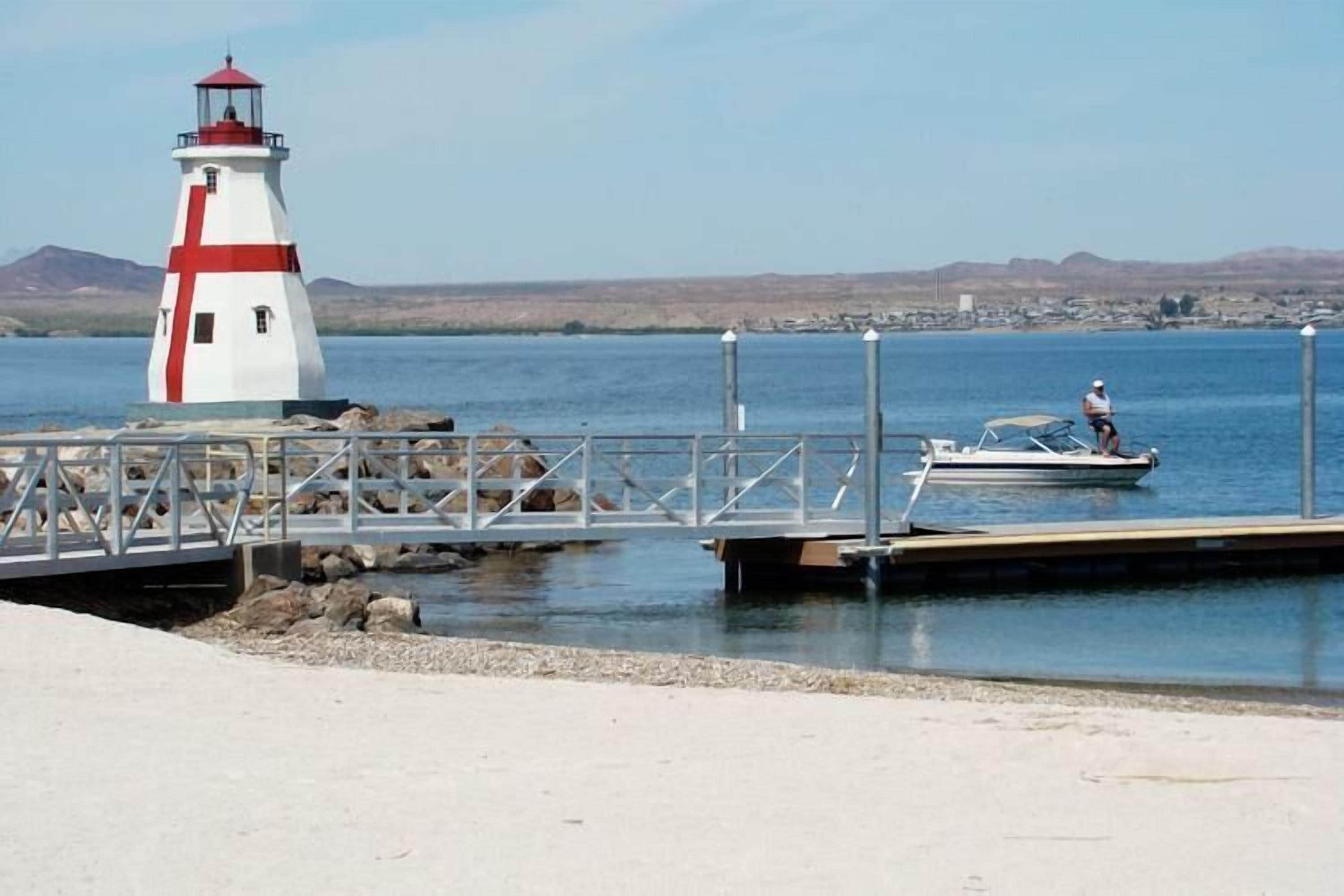 A lighthouse, a dock, and a person on a boat.