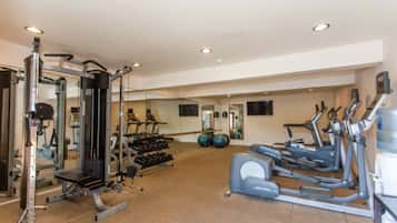A gym with cardio machines, weightlifting equipment, and a mirrored wall.