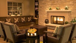 A cozy living room with a stone fireplace, a sofa, armchairs, and a coffee table. - Casa Munras Garden Hotel & Spa (Monterey)