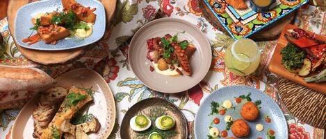 A table set with various dishes, including grilled fish, deviled eggs, and a colorful plate with bread and a drink.