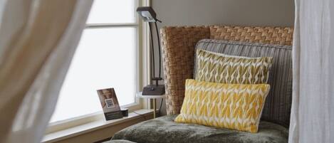A bedroom with a bed, bedside table, lamp, and a framed picture on the wall.