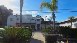 A building with a white facade, a central entrance, and a covered walkway. - Rodeway Inn Encinitas North (Encinitas)