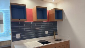 A kitchen with a marble countertop, a built-in microwave, and wooden cabinets. - Rodeway Inn Encinitas North (Encinitas)
