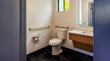 A bathroom with a toilet, a sink, a mirror, a window, and a towel rack.
