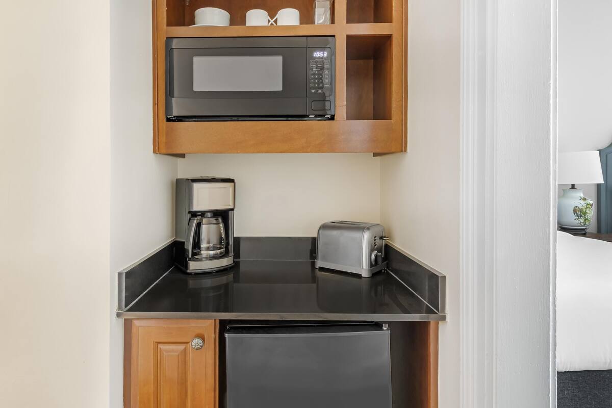 A compact kitchenette with a microwave, coffee maker, and toaster.