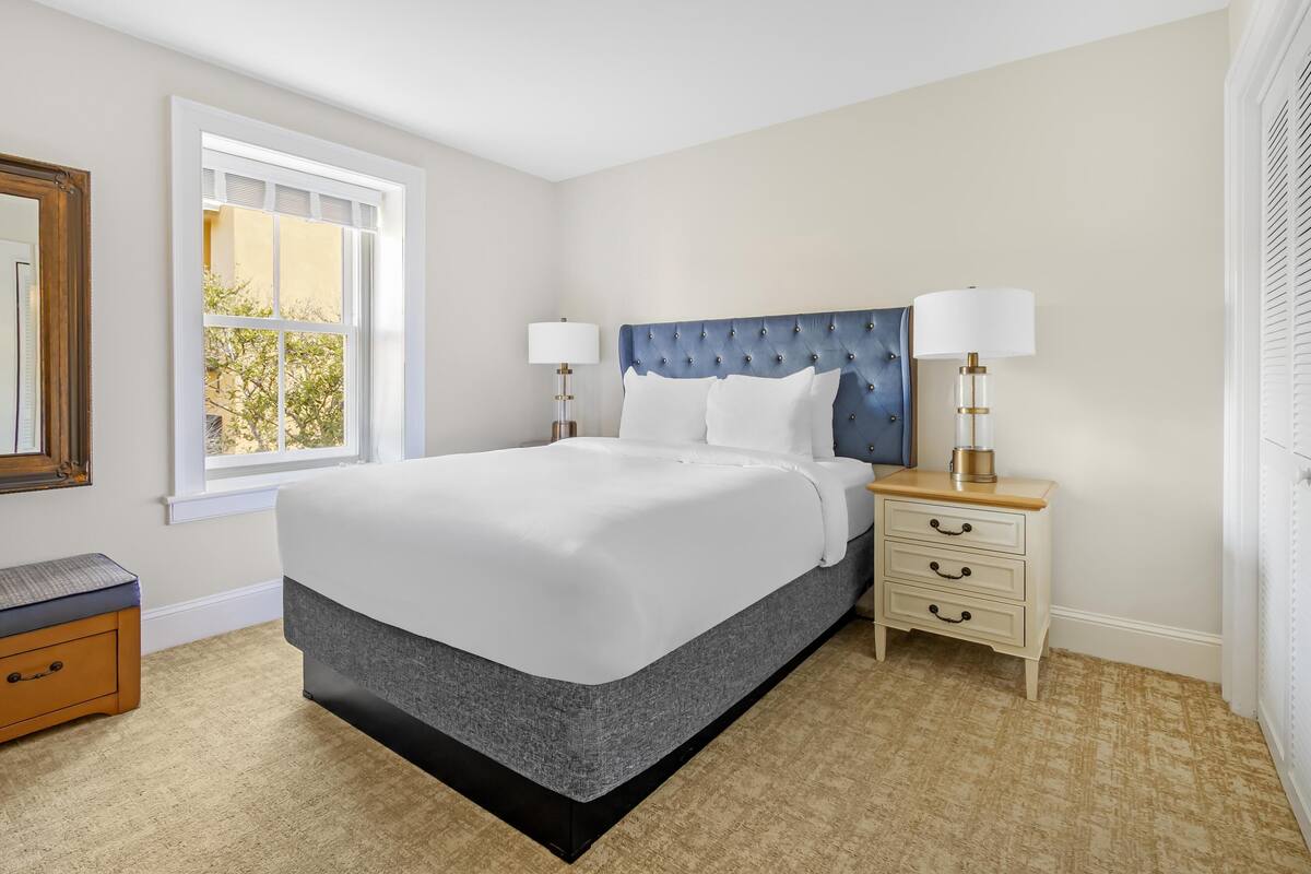 A bedroom with a bed, bedside tables, a window, and a mirror.