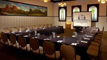 Uma sala de conferências no Hassayampa Inn com uma mesa comprida, cadeiras e uma tela de projetor exibindo o nome do hotel.