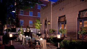 An outdoor patio area with tables and chairs, surrounded by buildings. - Hassayampa Inn (Prescott)