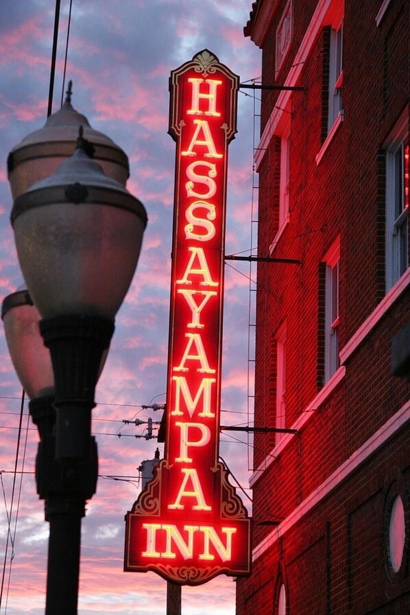 A neon sign for Hassayampa Inn against a sunset sky.