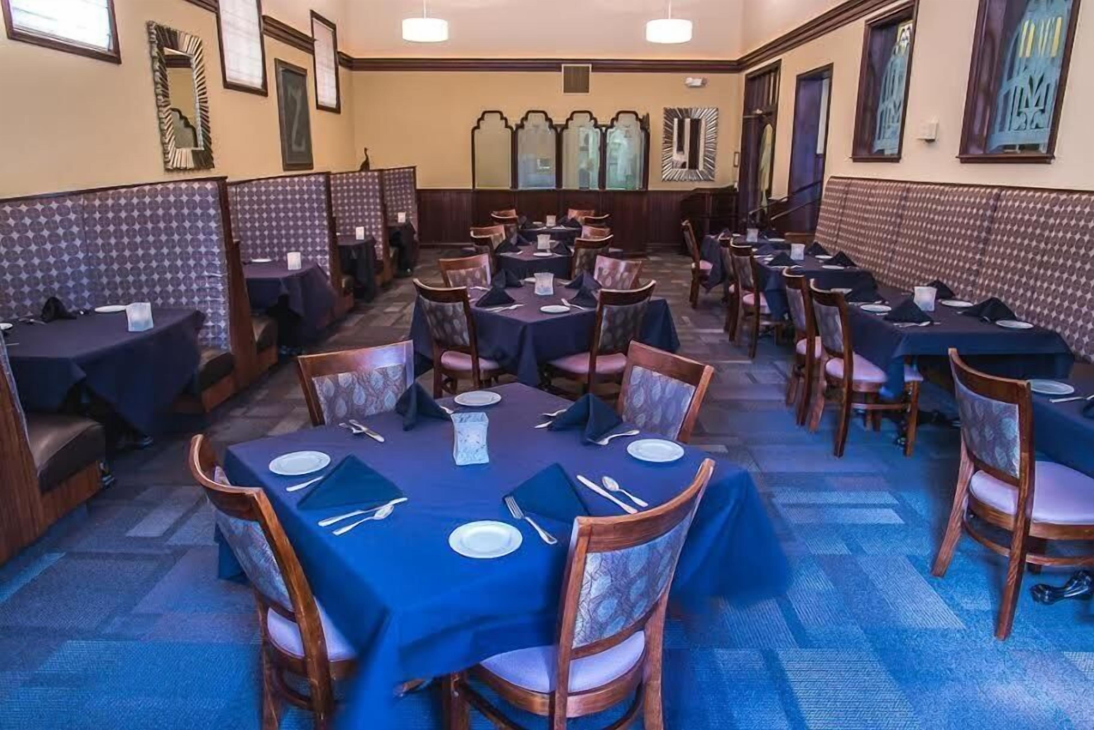 Un restaurant amb diverses cabines i taules, cadascuna amb estovell blau i plats blancs.