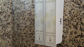Two Natura Aloe Vera body wash and conditioner boxes on a granite countertop.