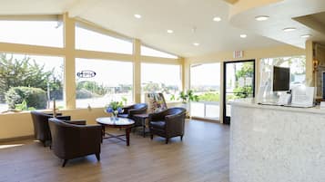 A spacious lobby with large windows, a reception desk, and several leather chairs.