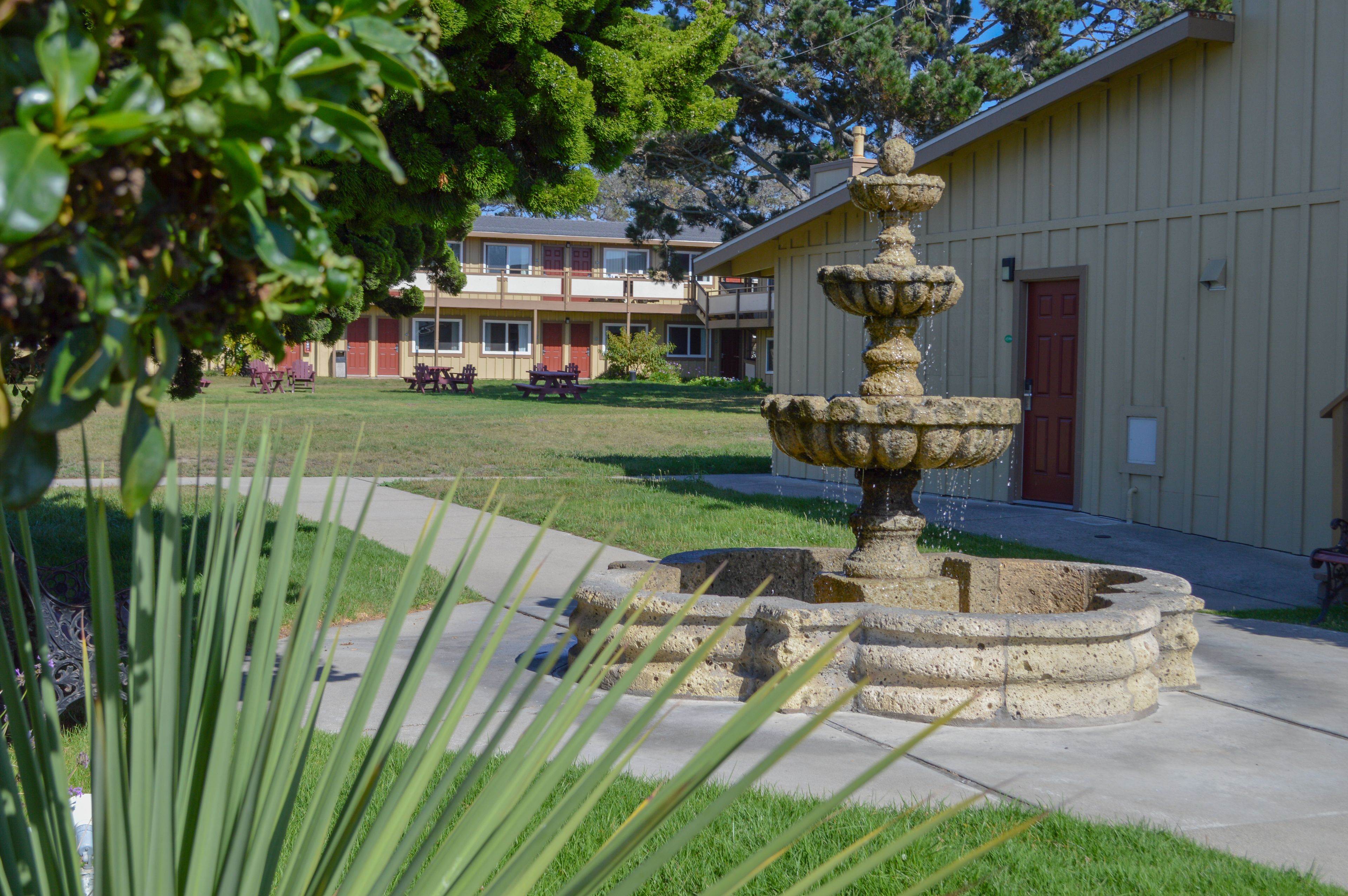 A stone fountain in a courtyard with a building in the background.