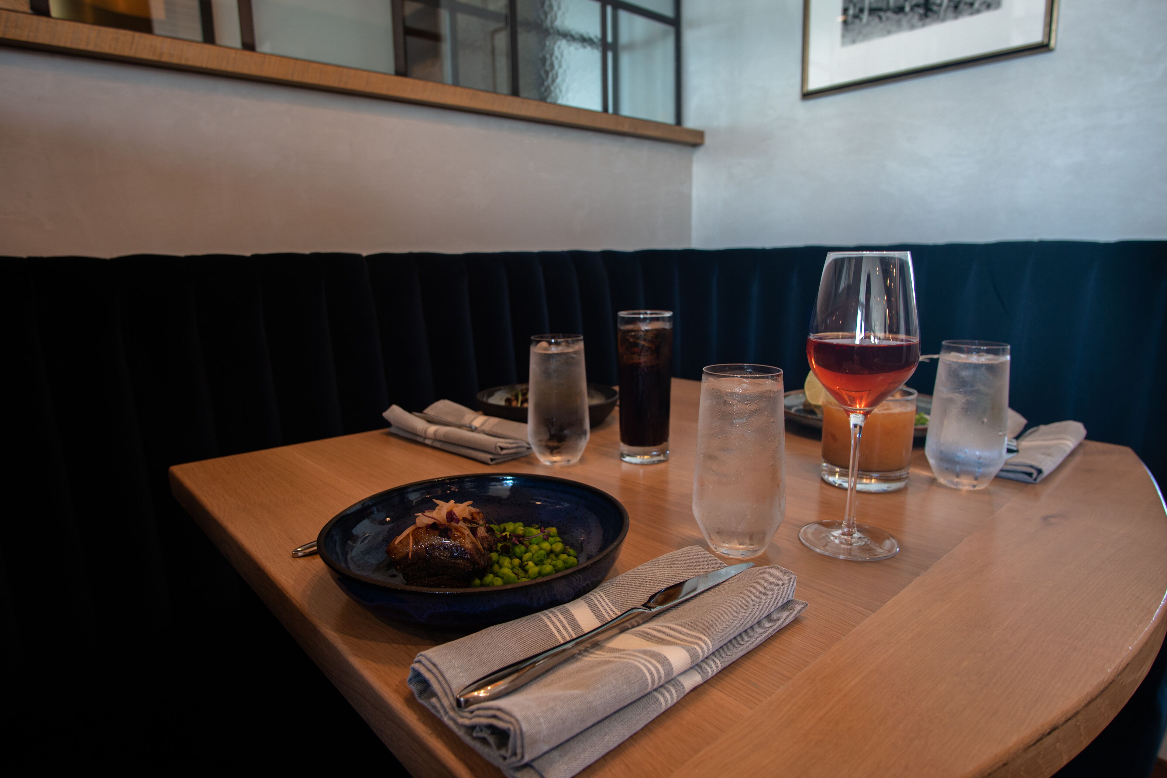 A dining table with a plate of food, a glass of red wine, and several glasses of water.