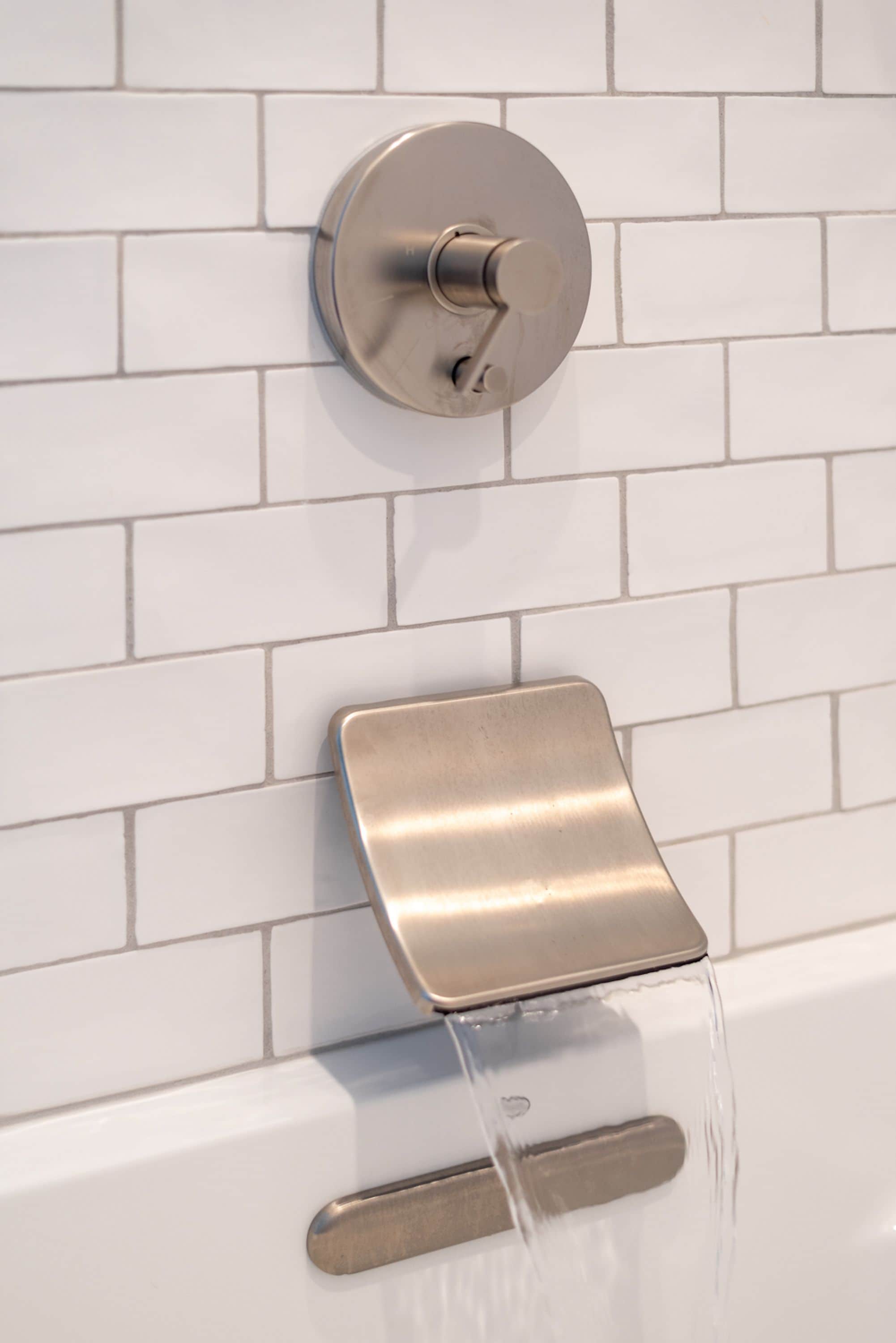 A modern bathroom with a wall-mounted faucet and a handheld showerhead.