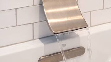 A modern bathroom with a wall-mounted faucet and a handheld showerhead.
