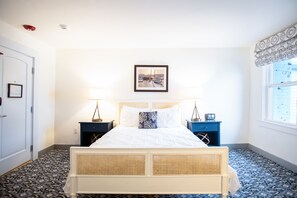 Classic hotel room with a large bed, bedside tables, and a framed picture above.