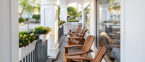 A covered outdoor seating area with wooden chairs and flower planters along the walls.