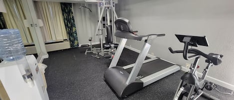 A gym with treadmills, a weight machine, and a water dispenser.