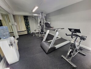 Un gimnasio con cintas de correr, máquinas de pesas y un dispensador de agua.