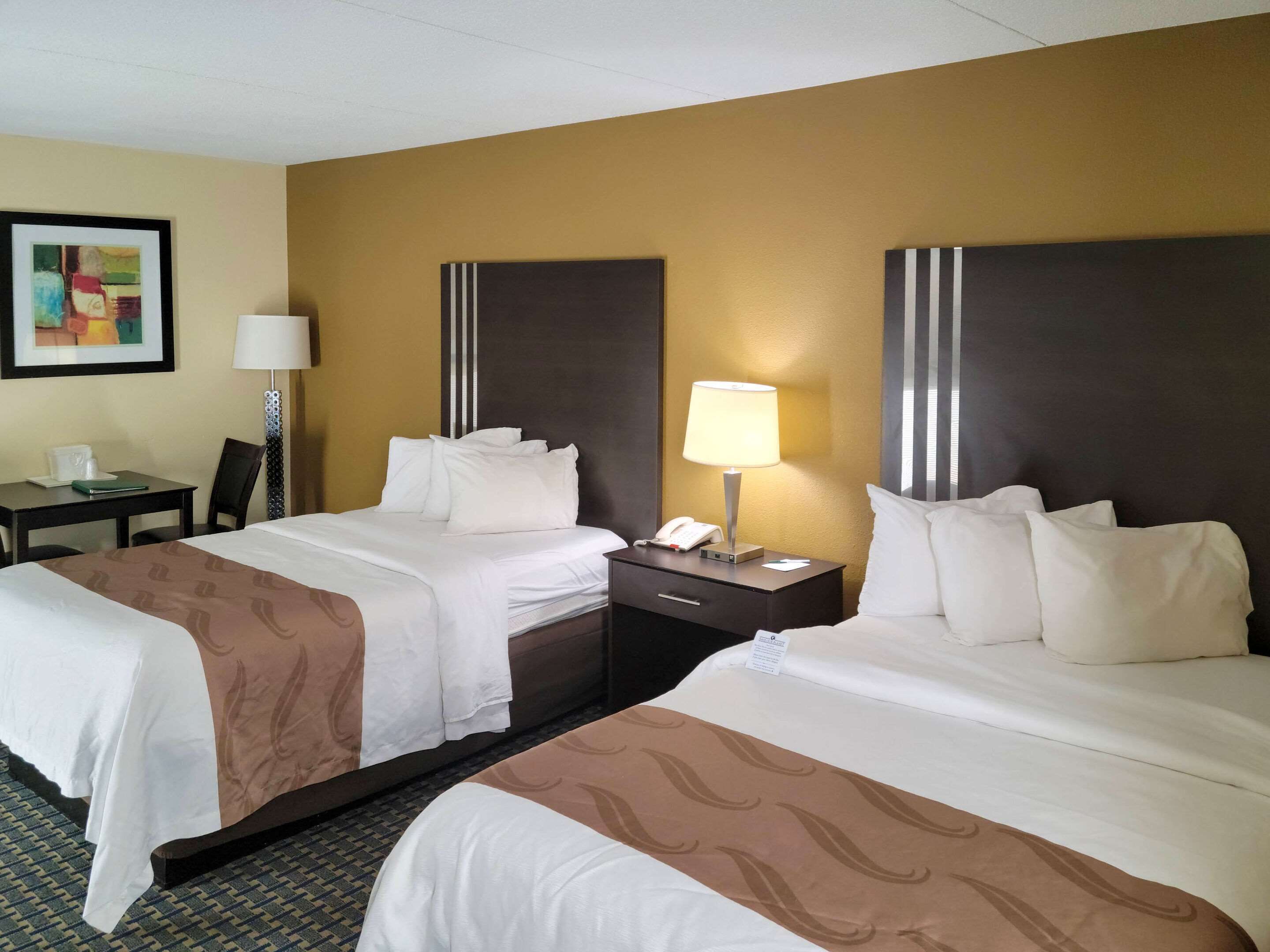 Habitación de hotel con dos camas, un escritorio y una silla.