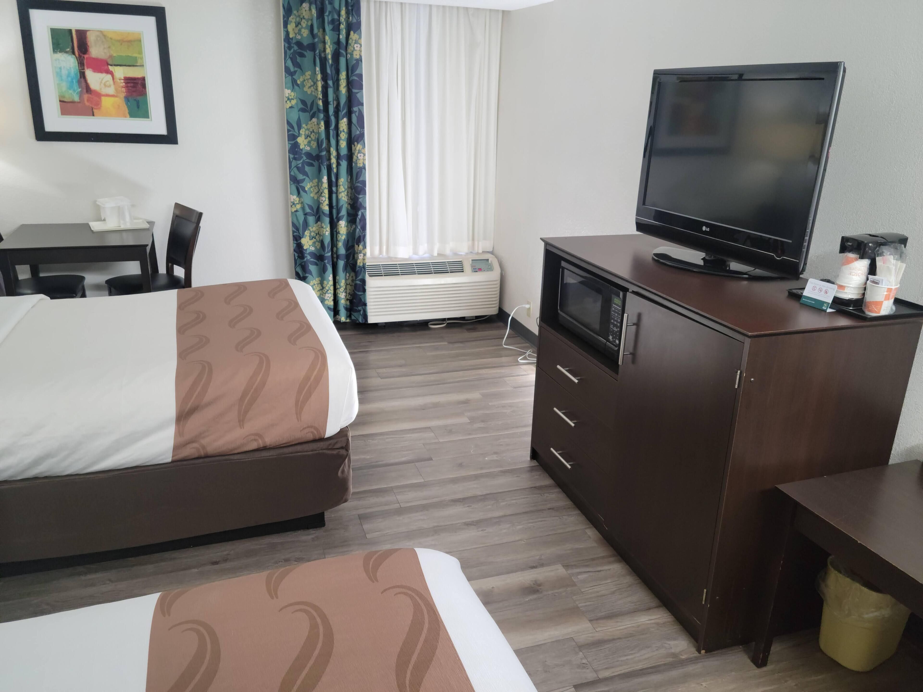 Una habitación de hotel con cama, escritorio, televisor y minibar.