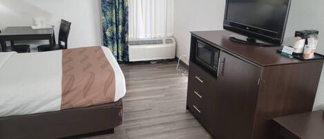 Una habitación de hotel con cama, escritorio, televisor y minibar.