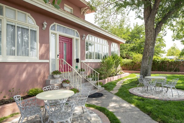 Charming two-story house with a front porch and lush garden surroundings.