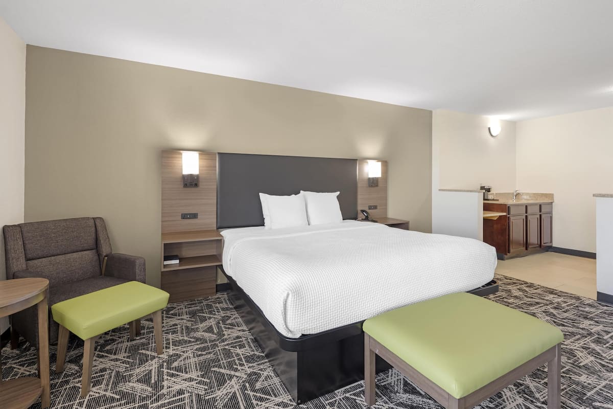 A hotel room with a large bed, a desk, a chair, and a small table.