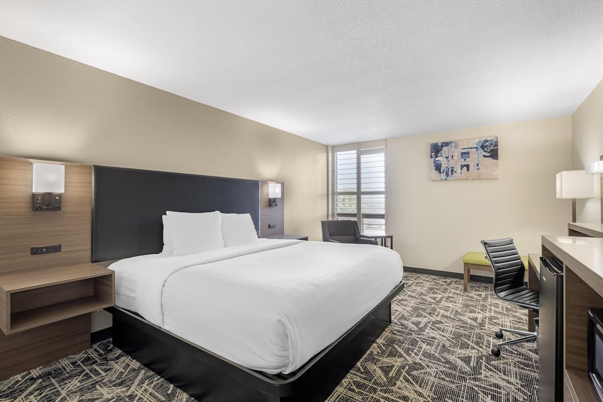 A hotel room with a large bed, bedside tables, a desk, and a chair.