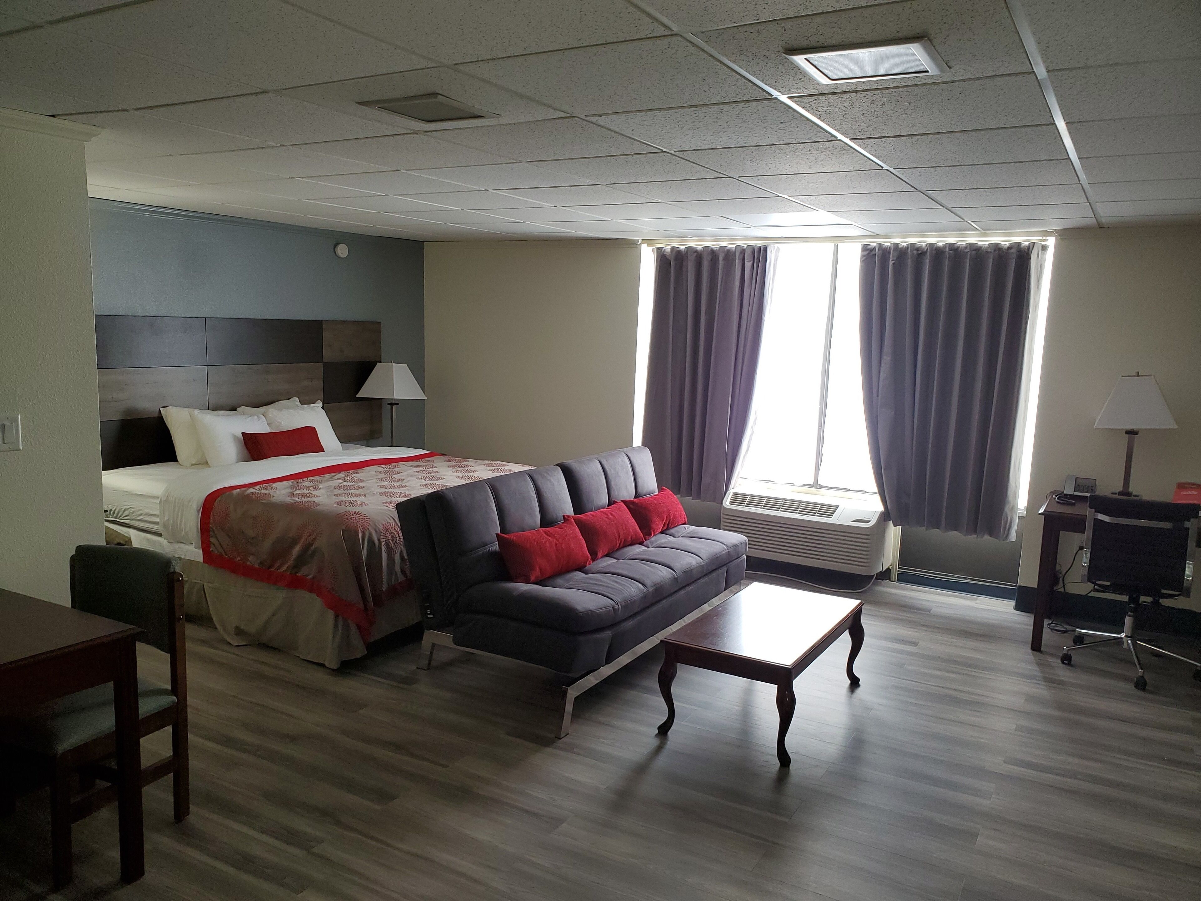 A hotel room with a bed, a sofa, a coffee table, a desk, and a chair.