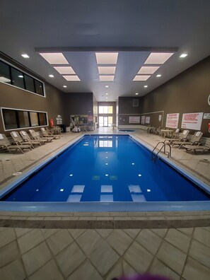 Relax by the pool with lounge chairs and tables surrounding the clear water.