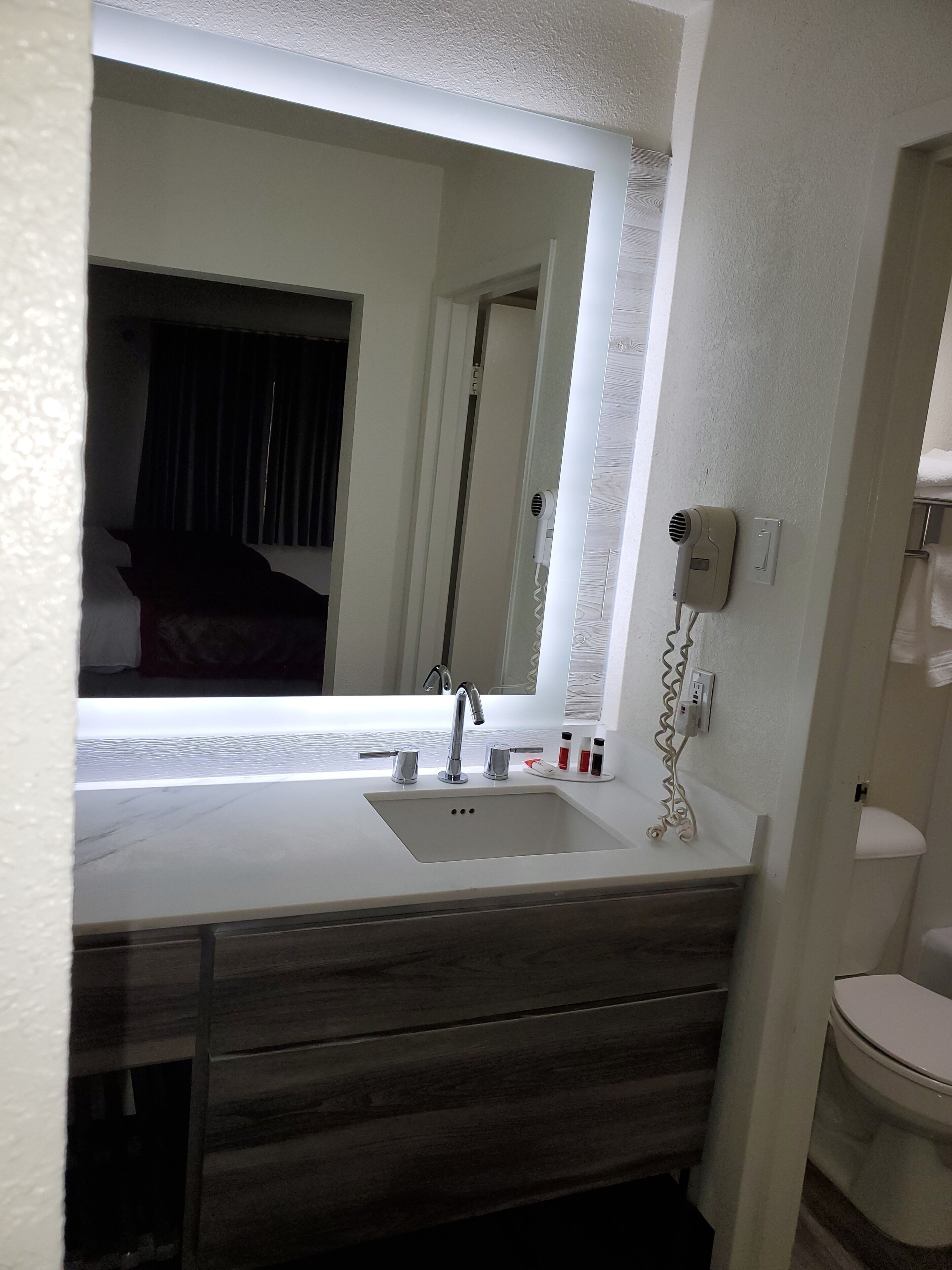 A bathroom with a white sink, a mirror, a hairdryer, and a toilet.