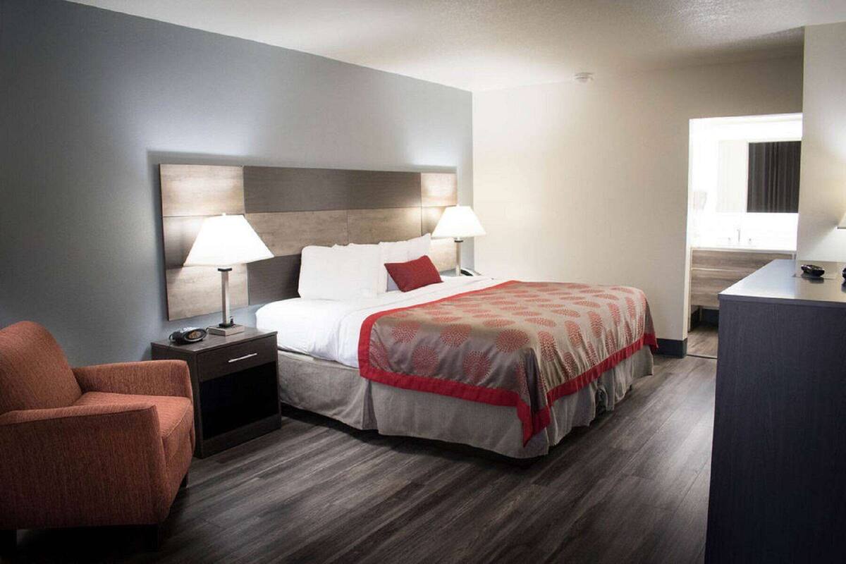 A hotel room with a bed, two bedside lamps, a nightstand, a chair, and a desk.