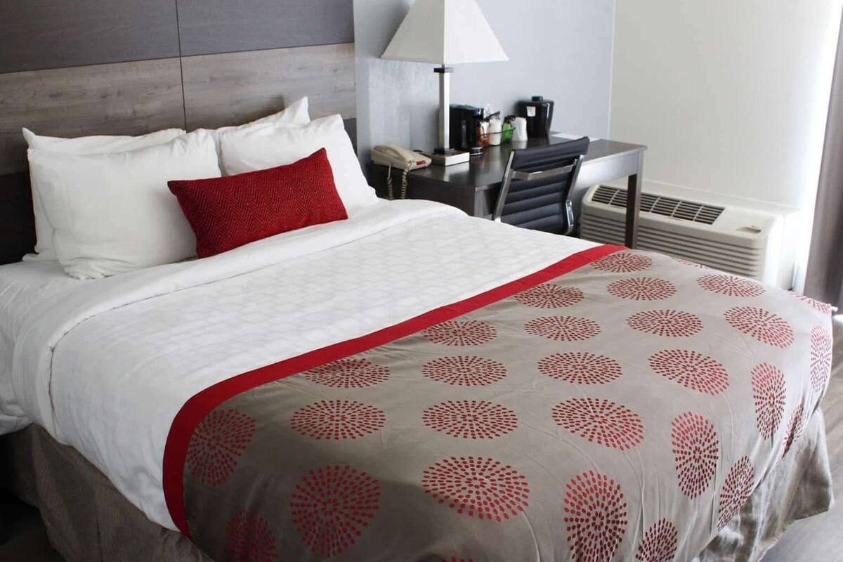 A hotel room with a bed, a desk with a lamp, a phone, and a coffee maker.