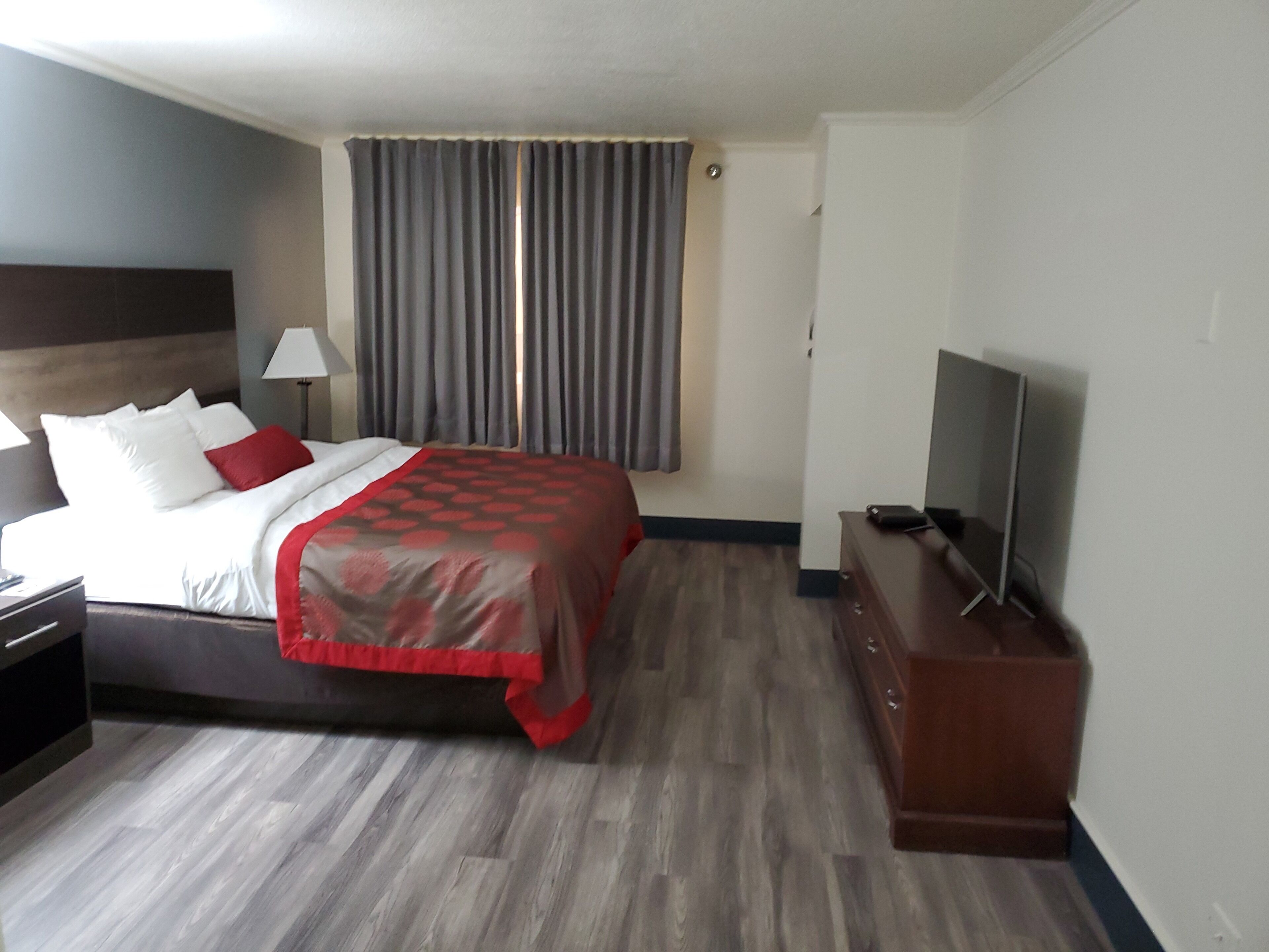 A hotel room with a bed, a TV, a desk, and a lamp.