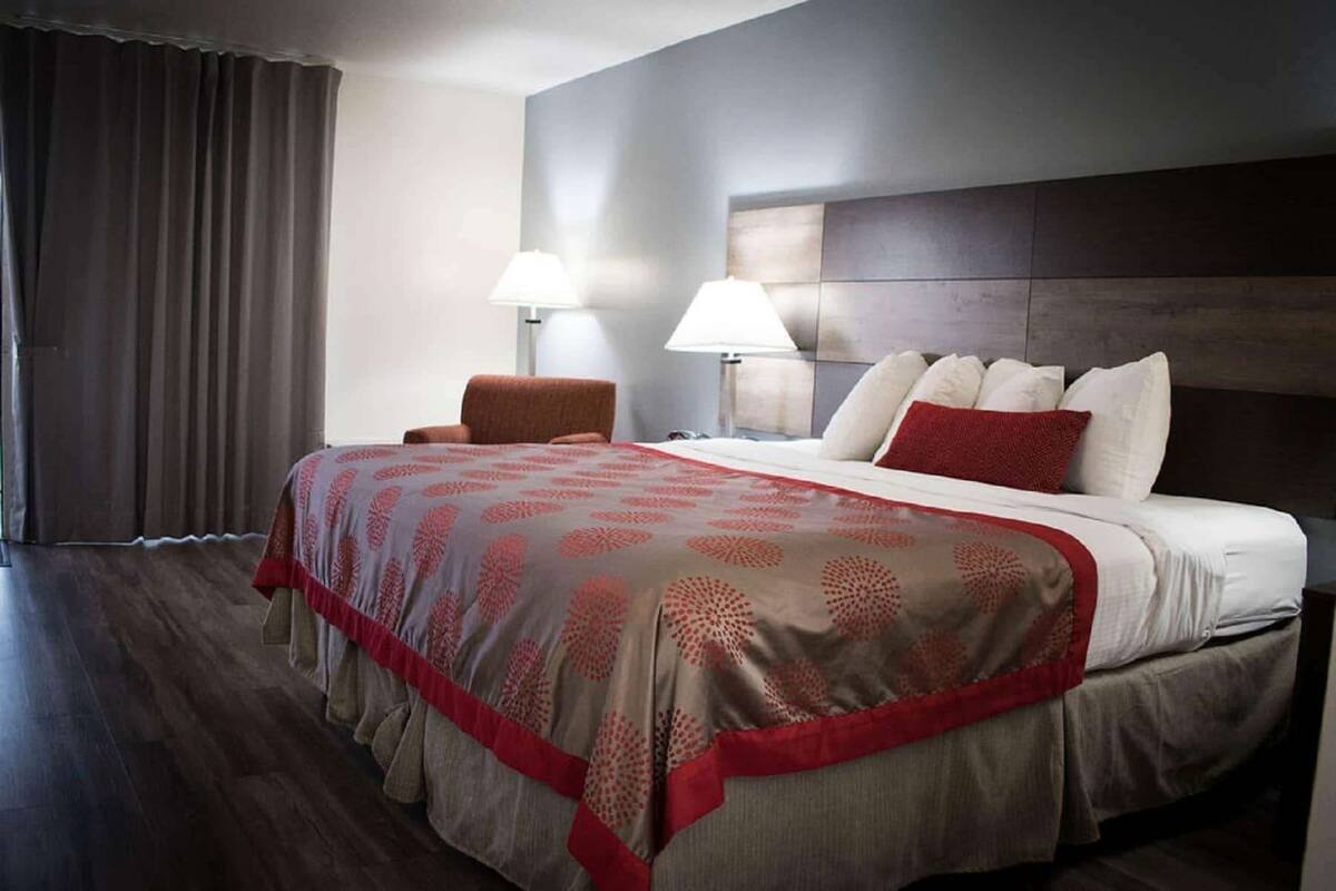 A hotel room with a large bed, two bedside lamps, a chair, and a view of the outside.